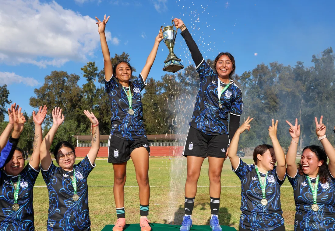 Equipo femenil celebrando con trofeo y medallas