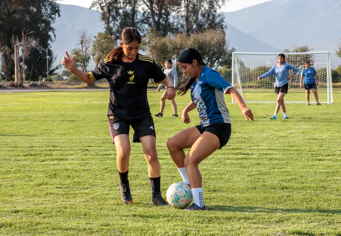 Jugadoras disputando el balón en partido de fútbol